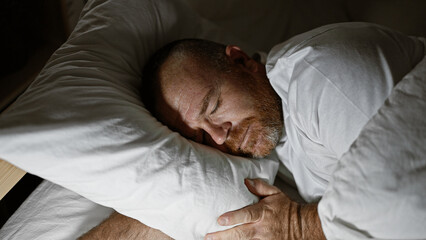 Handsome middle-aged caucasian man, comfortably resting in the cozy atmosphere of his bedroom, peacefully asleep engulfed in the soft morning light.