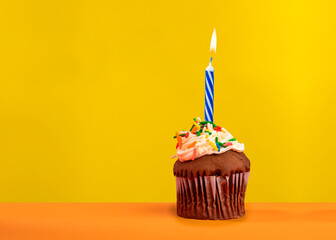 Birthday candle with cupcake on yellow color background