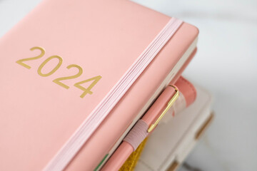 Pink coral colored diary for the year 2024, pen, marble background