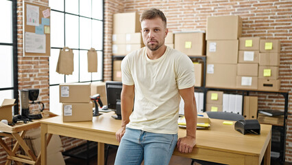 Young man ecommerce business worker standing with relaxed expression at office