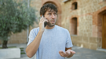 Handsome, bearded, blond young man, engrossed in a serious call on his smartphone at the green city...