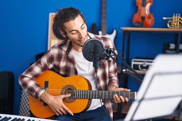 Young hispanic man musician singing song playing classical guitar at music studio