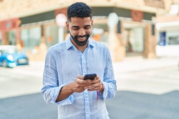 Young arab man smiling confident using smartphone at street