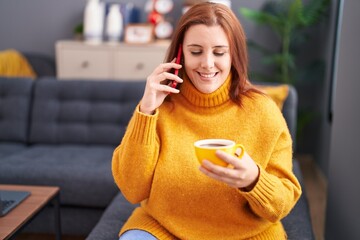 Young beautiful plus size woman talking on smartphone drinking coffee at home