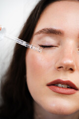 Girl with hyaluronic acid or serum pipette in hands close-up. Young woman is applying moisturizing serum on skin.