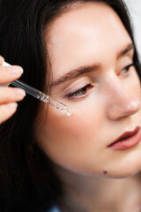 Girl with hyaluronic acid or serum pipette in hands close-up. Young woman is applying moisturizing serum on skin.