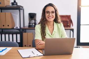 Young hispanic woman working at the office wearing glasses with a happy and cool smile on face....