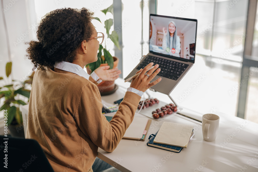 Wall mural Female freelancer have video conference with client while sitting in cozy coworking