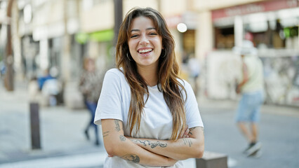 Young beautiful hispanic woman smiling confident standing with arms crossed gesture at street
