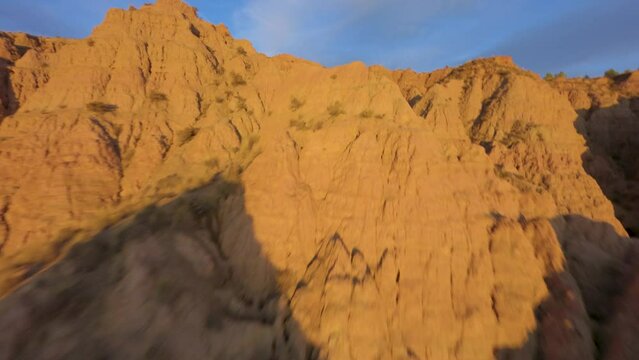 FPV drone flying low and fast at sunset among rocks in the badlands desert