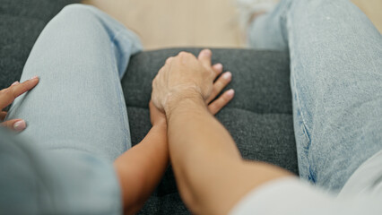 Man and woman couple sitting on sofa with hands together at home