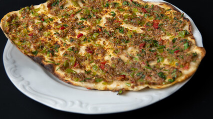Traditional delicious Turkish foods Home made lahmacun with mince lamb meat on white plate isolated on black background