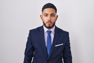 Young hispanic man wearing business suit and tie looking sleepy and tired, exhausted for fatigue and hangover, lazy eyes in the morning.