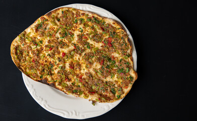 Traditional delicious Turkish foods lahmacun with mince lamb meat on white plate isolated on black background