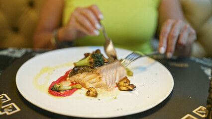 Middle age hispanic woman eating fish in a restaurant