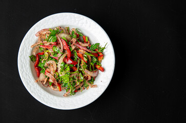 Salad with sliced lemon, onion, parsley, red pepper and tomatoes in porcelain bowl on dark background. Appetizer for Turkish pizza, pita pizza Lahmacun