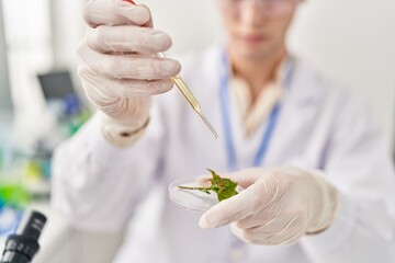 Young caucasian man scientist pouring liquid on plant sample at laboratory