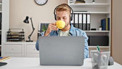 Young caucasian man business worker listening to music drinking coffee at office