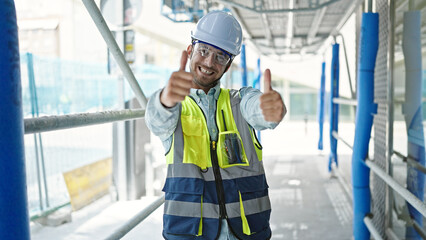 Young caucasian man architect holding doing thumbs up gesture at construction place