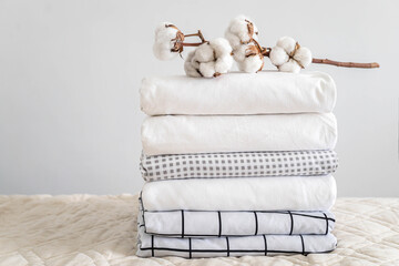 Cotton branch with pile of folded bed sheets and blankets - obrazy, fototapety, plakaty