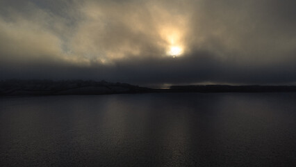 Aerial view of rutland Water reservoir lake as the sun sets in icy conditions with fog over the...