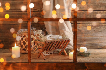 Manger with dummy of baby and candles on wooden background. Concept of Christmas story