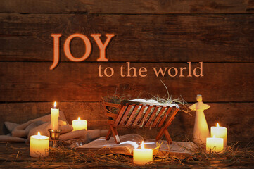 Manger with Holy Bible, angel toy and glowing candles on wooden background. Concept of Christmas...