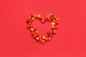 Heart made of sweet cherries on red background