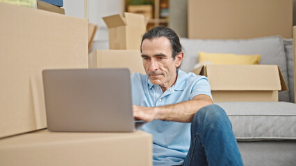 Middle age man using laptop sitting on floor at new home