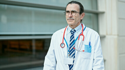 Middle age man doctor standing with serious expression at hospital