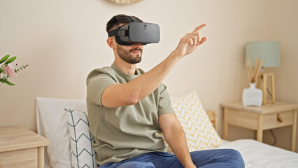 Young hispanic man using virtual reality glasses playing video game at bedroom