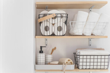 Beautiful white bathroom. Wooden shelves. Rolled towels, stacked towels and baskets. 