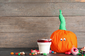 Paper pumpkin for Halloween. tasty panna cotta and candies on dark table