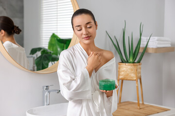 Young woman applying aloe gel onto her skin in bathroom