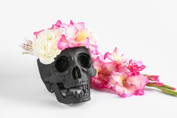 Black human skull with beautiful gladiolus flowers on white background
