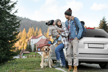Parents, their daughter and dog near car in mountains, space for text. Family traveling with pet