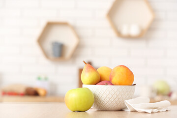 Bowl with ripe apples and pears on table in kitchen