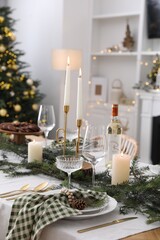 Christmas table setting with festive decor and dishware in room