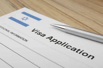 Immigration to Israel. Visa application form and pen on wooden table, closeup