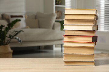 Stack of books on wooden table in living room, space for text. Home library