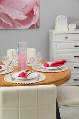Color accent table setting. Glasses, plates, jug of beverage and pink napkins in dining room