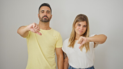 Man and woman couple doing thumb up gesture standing with serious face over isolated white background