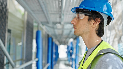 Young hispanic man architect wearing hardhat standing with serious face at construction place