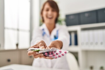 Young doctor woman holding pills smiling and laughing hard out loud because funny crazy joke.