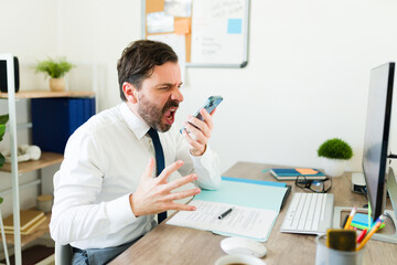 Angry boss with problems working at the office yelling talking on the phone