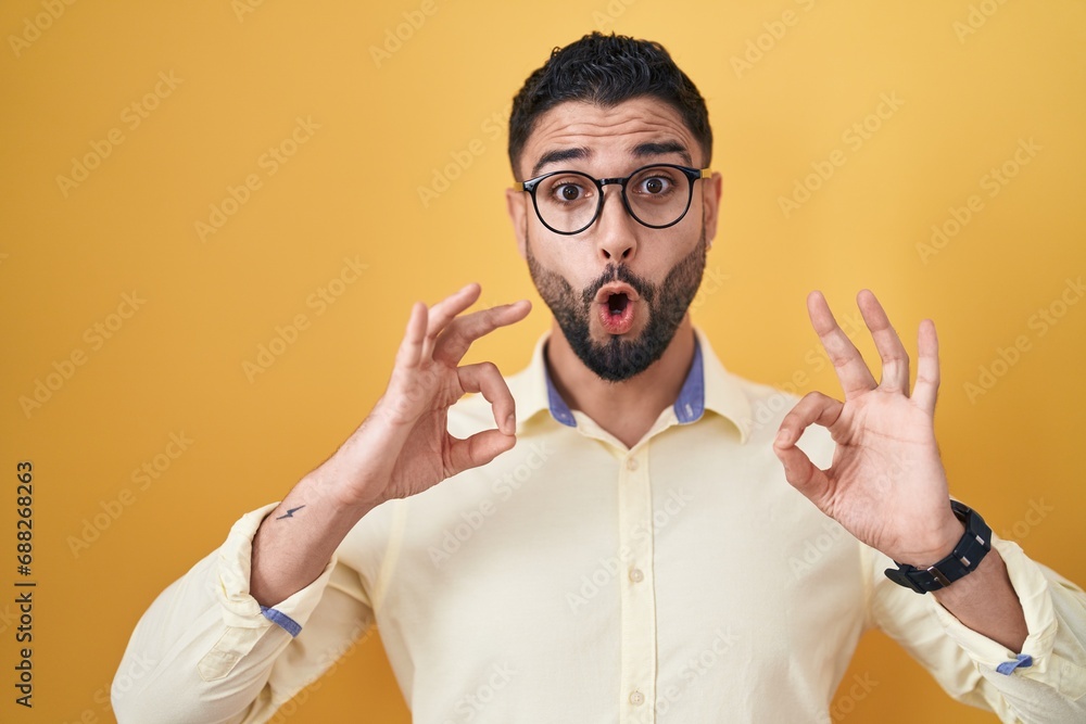 Canvas Prints hispanic young man wearing business clothes and glasses looking surprised and shocked doing ok appro