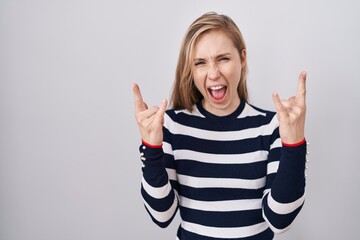 Young caucasian woman wearing casual navy sweater shouting with crazy expression doing rock symbol...