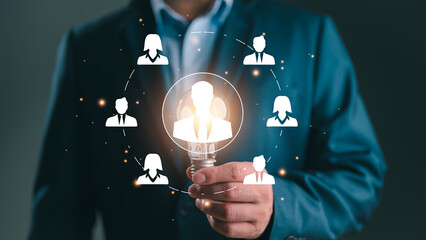 Businessman showing virtual human icon on lightbulb for business CRM or Customer Relation...