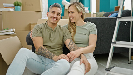 Obraz premium Man and woman couple hugging each other sitting on floor at new home