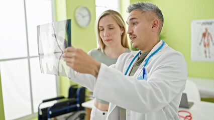 Fototapeta premium Man and woman doctor and patient having medical consultation looking xray at the clinic